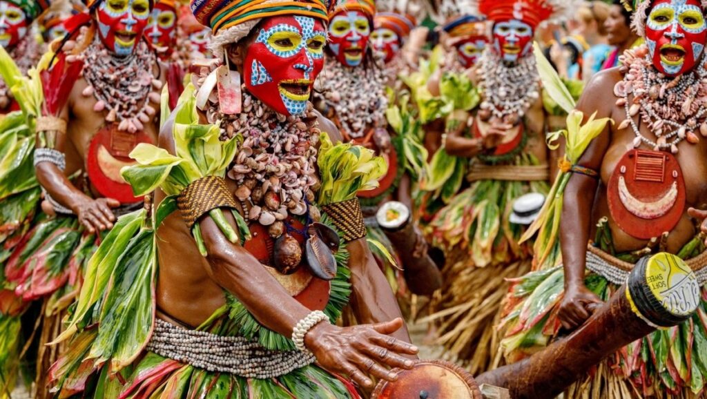 Papua New Guinean performers in traditional dress and body paint celebrating cultural heritage, symbolizing efforts to preserve indigenous languages in modern times.
