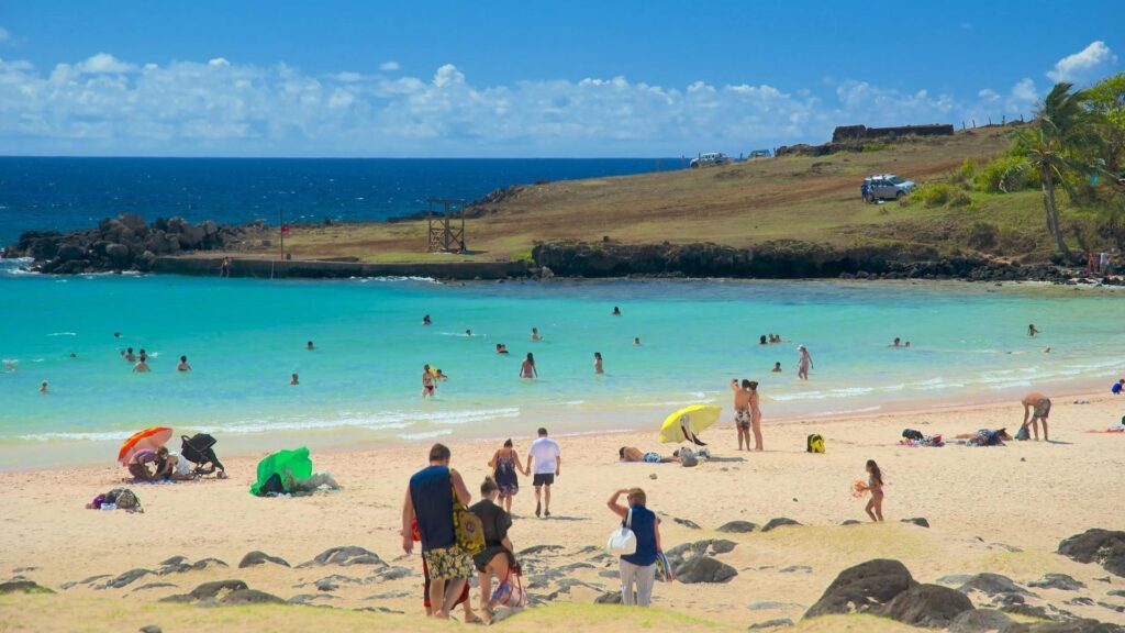 Hanga Roa - easter island Visitors relaxing and swimming at Hanga Roa Beach on Easter Island, surrounded by turquoise water and volcanic hills.