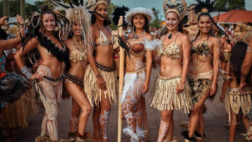 Rapa Nui Traditional Clothing - easter island Rapa Nui women wearing traditional skirts, body paint, and feathered adornments during a cultural dance festival on Easter Island.