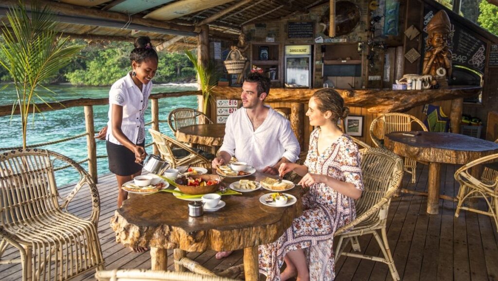 Tourists enjoying a meal at a seaside restaurant in the Solomon Islands, showcasing Pacific hospitality