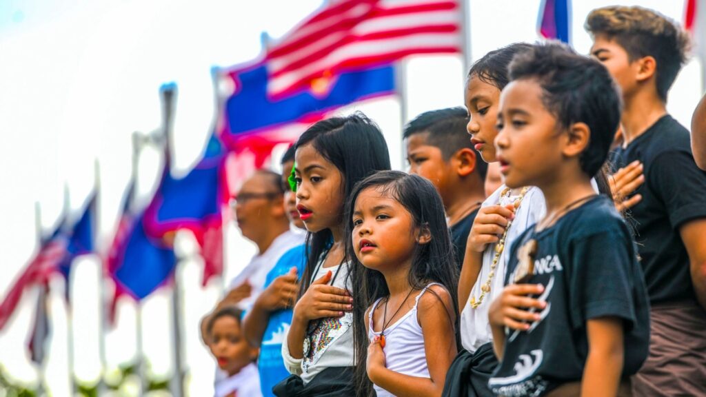 Guam kids standing in front of Guam and US flag
