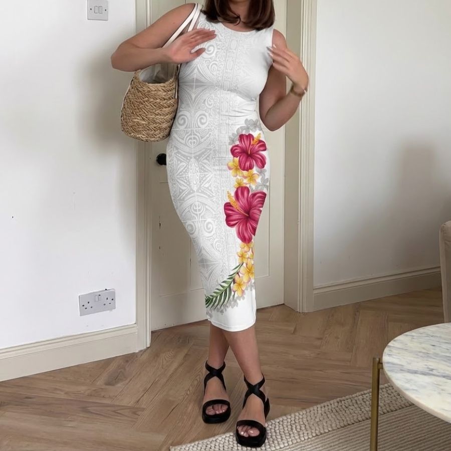 Woman wearing white sleeveless bodycon midi dress with bright pink and yellow hibiscus floral print, carrying straw bag and wearing black platform sandals