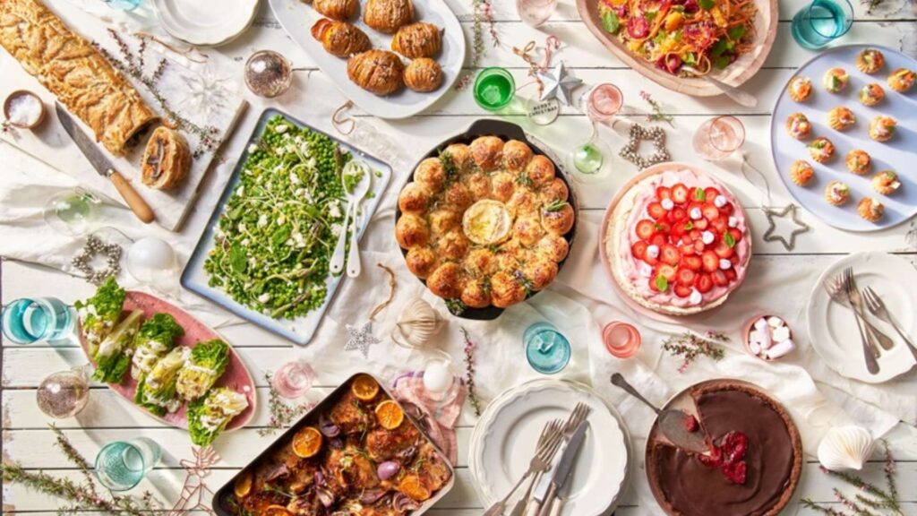 A festive New Zealand Christmas spread featuring pavlova, roast meats, salads, seafood, and summer-inspired dishes arranged on a bright holiday table.