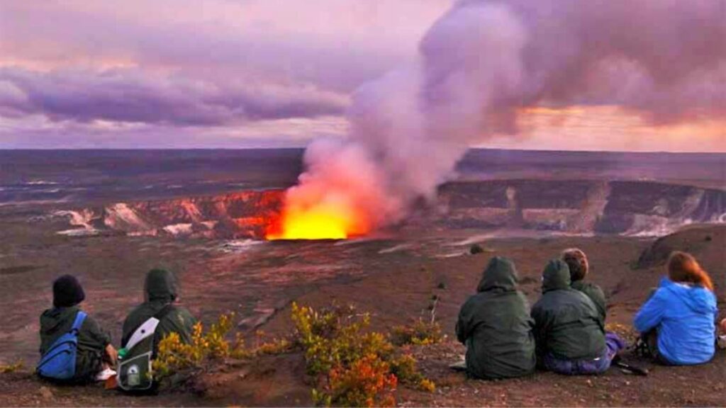 Visitors watching the glowing Kīlauea crater at Hawaiʻi Volcanoes National Park at sunset on the Big Island